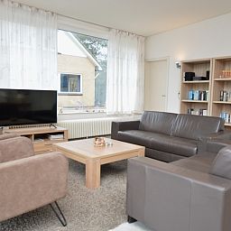Bright living room with bookcase in vacation home Epelaan 31, De Koog, Texel, perfect for reading lovers.