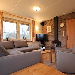 Gezellige woonkamer in Villa, De Koog, Texel, met comfortabele zithoek en open haard voor een knus verblijf.