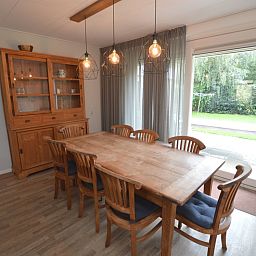 Dining area in Orchismient 27, De Koog, Texel, with wooden table and garden view.