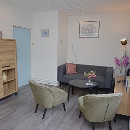 Modern living room in vacation home Plevierstraat 18, De Koog, Texel with comfortable seating area and wooden cupboard.