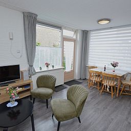Bright dining and living room in vacation home Plevierstraat 18, De Koog, Texel with dining table and television.