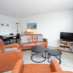 Attraktiv eingerichtetes Wohnzimmer im Motel Texel - Apartment 208/1L, De Koog, Texel, mit Ledersitz und Essecke.