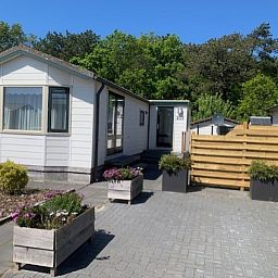 Vacation home Chalet Bregkoog 203, located in De Koog, Texel, with spacious driveway and green surroundings.