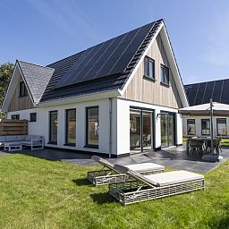Geniessen Sie die Sonne auf dem gruenen Rasen und der Terrasse der Villa 19, einem Ferienhaus in De Koog, Texel, umgeben von Natur.