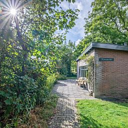 Veranda des Ferienhauses De Zonneweelde in De Koog, Texel, mit gruener Umgebung und Sitzgelegenheiten.