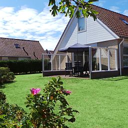 Enjoy the green garden and terrace of Villa 5, De Koog, Texel, perfect for relaxing outdoor activities.