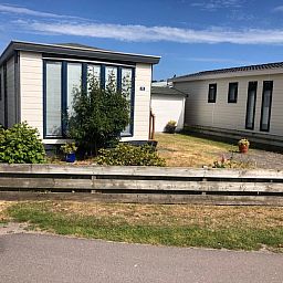 Rustic vacation home Chalet Bregkoog 33 on Chaletpark Bregkoog, located in picturesque De Koog, Texel, surrounded by greenery.