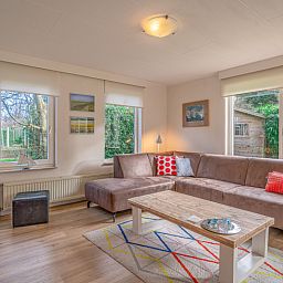 Gemuetliches Wohnzimmer im Ferienhaus Kamperfoelie 29, De Koog, Texel, mit Blick auf den Garten.