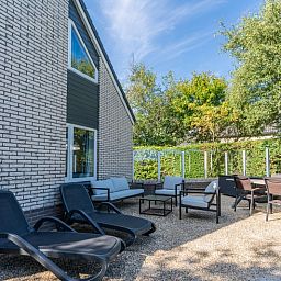 Sunny terrace at Holiday home Kamperfoelie 55 in De Koog Texel with comfortable deck chairs.