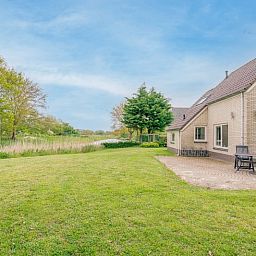 Spacious terrace at Holiday home Honeysuckle 45, De Koog, Texel, overlooking a green garden.