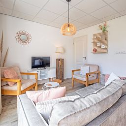Stylish sitting area in De Duinroos vacation home, Texel, with modern furnishings and television.
