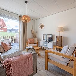 Bright living space in De Duinroos vacation home on Texel overlooking the terrace.