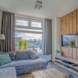 Bright living room of De Bosruiter vacation home in De Koog Texel with a view of the street and a cozy sitting area.