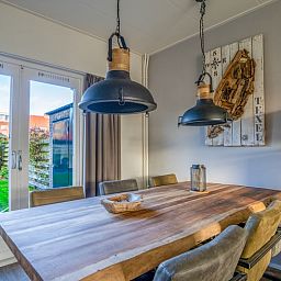 Dining room in De Bosruiter vacation home, De Koog Texel, with wooden table and access to the garden through French doors.