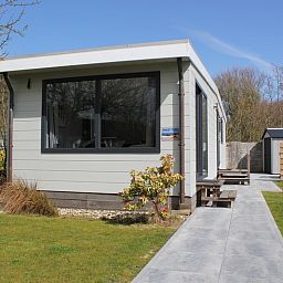 Chalet Bregkoog 208, ein Ferienhaus in De Koog, Texel, mit einer einladenden Veranda und einem Gartensitzplatz.