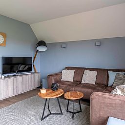 Stilvolle Sitzecke im Ferienhaus Nieuwlanderweg 77, De Koog, Texel, mit bequemem Sofa und Flachbildfernseher, ideal zum Entspannen.