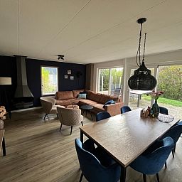 Stijlvolle woonkamer van De Duinven in De Koog, Texel, met uitzicht op de tuin, perfect voor familiebijeenkomsten.