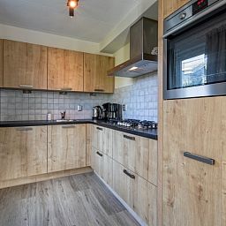 Volledig uitgeruste keuken in De Duinven vakantiehuis, De Koog, Texel, met houten afwerkingen en moderne apparatuur.
