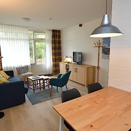 Spacious interior of Apartment Kerckeland 126 in De Koog, Texel, with dining area and view of the greenery.