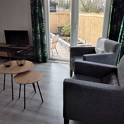 Cozy living room in Chalet Uit en Thuis, De Koog, Texel, with comfortable chairs and views of the terrace.