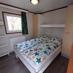 Attractive bedroom in Chalet Uit en Thuis, De Koog, Texel, with double bed and colorful blankets.