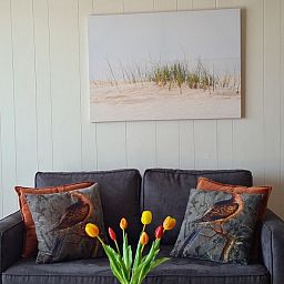 Stilvolle Sitzecke im Motel Texel Apartment Y, De Koog, Texel, mit Kunstwerken und bunten Kissen.