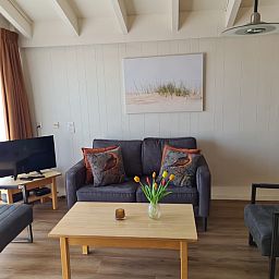 Modernes Wohnzimmer des Motel Texel Apartment Y in De Koog, Texel, ausgestattet mit einem bequemen Sofa und einem Fernseher.