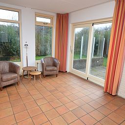 Spacious living space in Holiday home Stappeland 199, De Koog, Texel, with large windows and views of the garden.