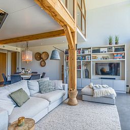 Open living room in Holiday Home in De Koog with comfortable sitting area and bookshelves.