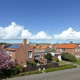 Blick von Apartments Anna - Apartment 15 in De Koog, Texel, mit charmanten Haeusern und blauem Himmel.