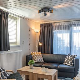 Gemuetliches Wohnzimmer im Bungalow 1, De Koog, Texel mit stilvollen Moebeln und viel Tageslicht.