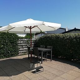 Veranda of Chalet Bregkoog 47 'De Muy' in De Koog, Texel. Enjoy the outdoors on the terrace with parasol.