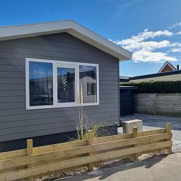 Chaletpark Bregkoog - Chalet 45 TX45 in De Koog, Texel, charmante Fassade mit Holzzaun und sonniger Lage.