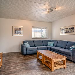 Cozy sitting area in Orchismient 2, vacation home Texel, with large sofa and wooden coffee table.