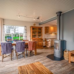 Open kitchen and dining area in Orchismient 2, vacation home De Koog, Texel with wood stove and large windows.