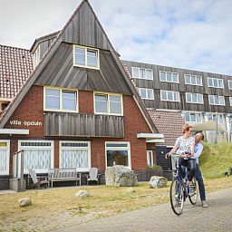 Exterior of Grand Hotel Opduin - Apartment C in De Koog, Texel, with charming architecture and cycling guests.