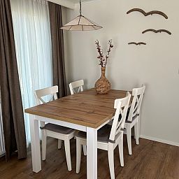Essecke im Chalet Bregkoog 213 auf Texel, Chaletpark Bregkoog, mit Holztisch und modernen Stuehlen.