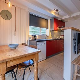 Modern kitchen in vacation home 32b Pollux, De Koog, Texel with dining area and bright red accents.