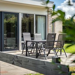 Veranda von Bungalow 19A in De Koog, Texel mit modernem Gartentisch und Stuehlen, perfekt fuer ein Essen im Freien auf den Watteninseln.