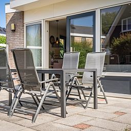 Terrasse von Bungalow 19A in De Koog, Texel mit Glasschiebetueren zum Innenraum, ideal fuer einen Urlaub in der Natur.