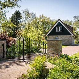 Entrance to Landhuis De Wije Blick, vacation home in De Koog, Texel, with entrance gate and lush surroundings.