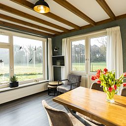 Bright dining room of De Koperwiek in De Koog Texel overlooking green fields.