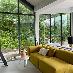 Cozy sitting area in De Koerie vacation home De Koog Texel with comfortable sofa and green surroundings.