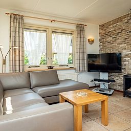 Gemuetliches Wohnzimmer der Villa mit Wintergarten in De Koog, Texel, mit Kamin und gemuetlicher Sitzecke.