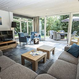 Bright living room of Westenwind vacation home in De Koog, Texel with comfortable seating area and view of the terrace.