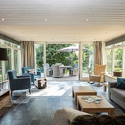Sunny living room of Westenwind vacation home in De Koog, Texel with large windows and garden view.