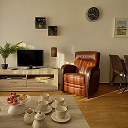 Helles und geraeumiges Wohnzimmer in De Pelikaan Apartments, De Koog, Texel mit stilvollen Moebeln und Dekorationen.