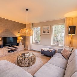 Gemuetliches Wohnzimmer des Ferienhauses Kamperfoelie 73 in De Koog, Texel mit bequemen Sofas und moderner Einrichtung.