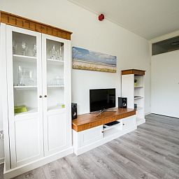 Stilvolles Wohnzimmer in 't Kerckeland - Apartment Kerckeland 88, De Koog, Texel mit Unterhaltungsmoeglichkeiten und Glasschrank.