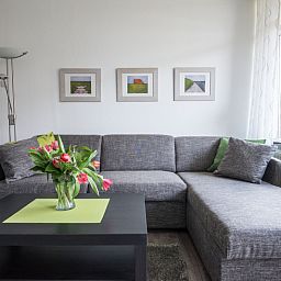 Gemuetliche Sitzecke in 't Kerckeland - Apartment Kerckeland 88, De Koog, Texel mit bequemem Sofa und dekorativen Kunstwerken.